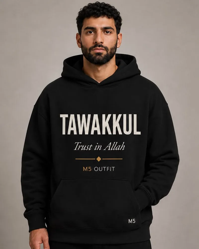 Model wearing a black M5 Outfit hoodie printed with the Arabic and English word Tawakkul