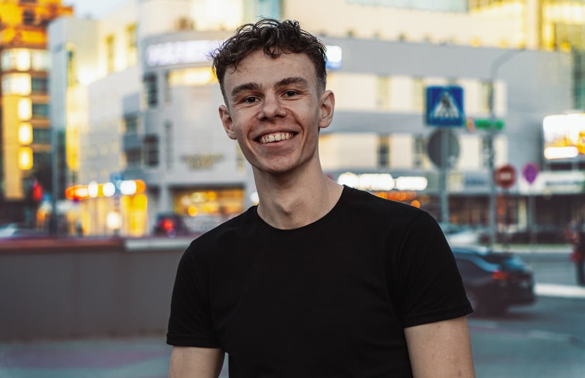 Model wearing an M5 Outfit black crew tee, smiling on a city street